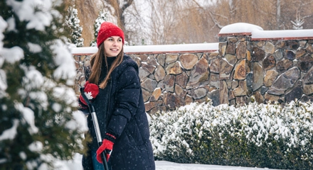 Young woman cleans snow yard snowy weather