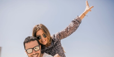 Man taking photograph her girlfriend enjoying piggyback ride his back