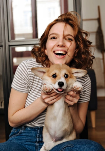 Positive woman sits floor living room with smile plays with her beloved dog