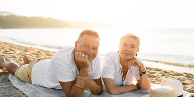 Full shot couple laying towel beach